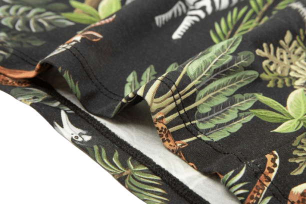 Close-up of a black fabric featuring vibrant jungle-themed prints of leaves and animals like zebras and leopards.