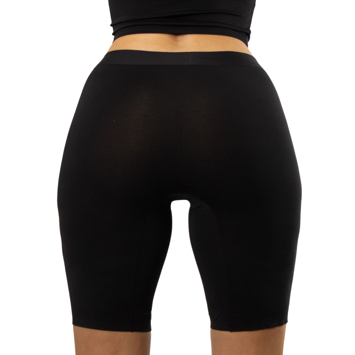 Model wearing PureSnug\s black high-waisted biker shorts, viewed from the back, showcasing a smooth silhouette against a white background.