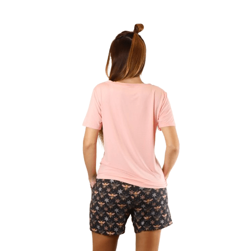 A woman stands with her back to the camera, wearing a pink t-shirt and patterned shorts, showcasing a casual loungewear look.