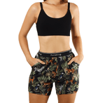Woman in black sports bra and tropical shorts with hands in pockets, showcasing a vibrant, nature-inspired design.