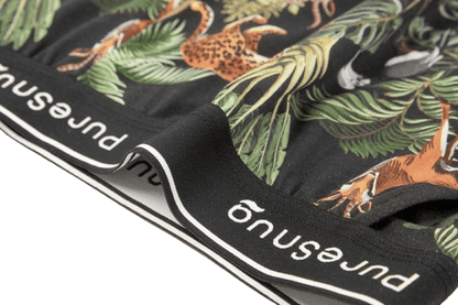 Close-up of women's underwear featuring a vibrant jungle print with animals and plants, showcasing a black waistband labeled "PureSnug"