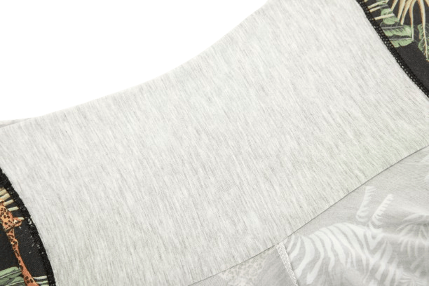 Close-up of a garment featuring a light gray fabric with a patterned edge showcasing leaves and animal prints.