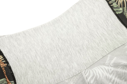 Close-up of a garment featuring a light gray fabric with a patterned edge showcasing leaves and animal prints.
