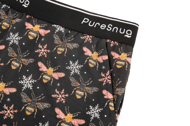 Close-up of patterned fabric featuring bees and snowflakes, with a black waistband labeled "PureSnug."