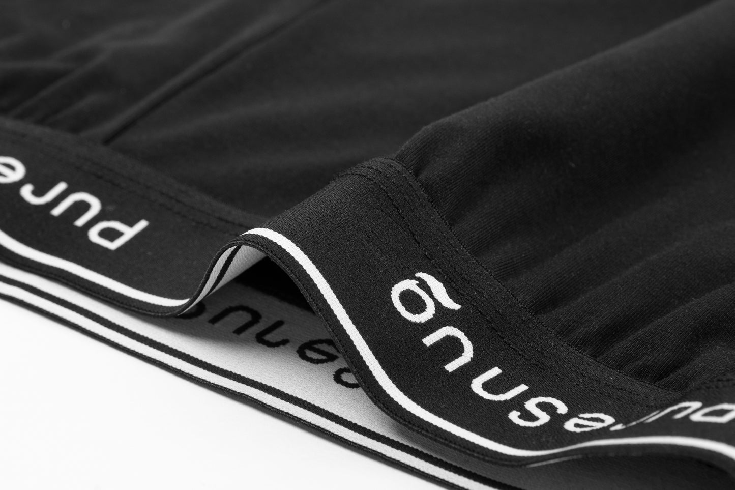 Close-up of black lounge shorts with a white waistband displaying the brand name "PureSnug"