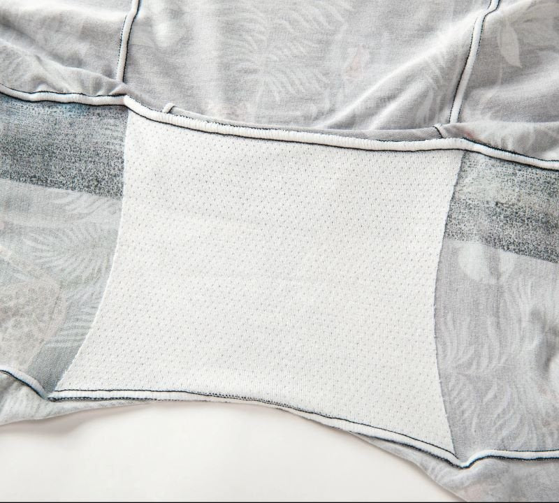 Close-up of a light grey and white gusset fabric showing intricate stitching and faint floral patterns