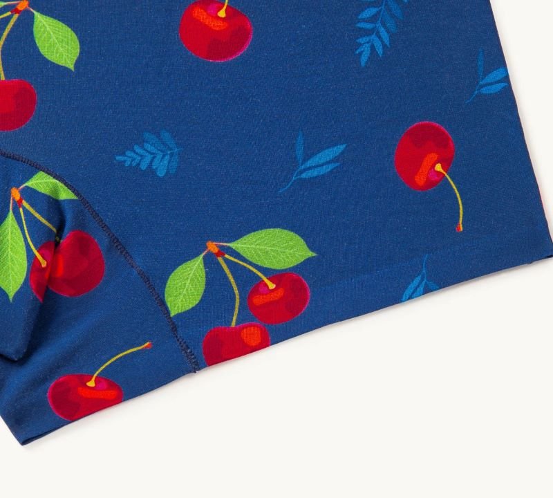 Close-up of navy blue fabric featuring a whimsical pattern of bright red cherries with green leaves.