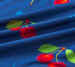 Blue fabric with a vibrant cherry pattern, featuring red cherries and green leaves.