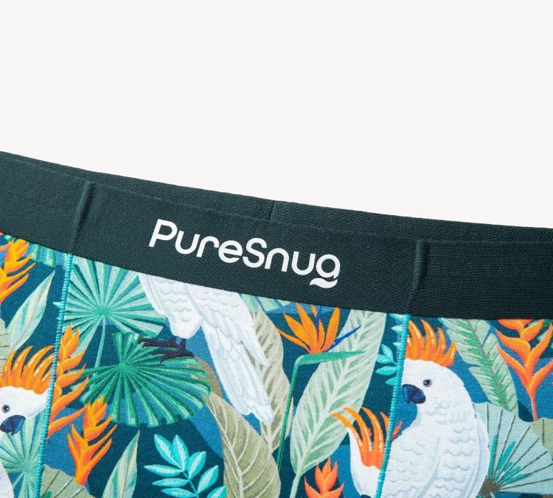 Tropical underwear with cockatoos, orange and blue leaves, and a PureSnug logo waistband.