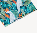 Tropical fabric with white cockatoos, orange crests, green leaves, and bright orange flowers.