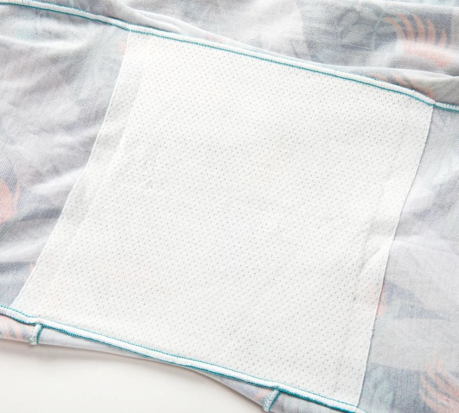 Soft light fabric with pastel blue trim and a textured white patch, simple and clean.