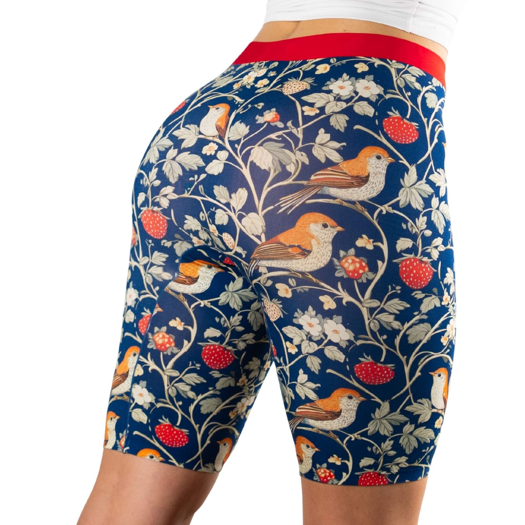 A close-up of a woman's backside wearing patterned shorts featuring birds and strawberries against a dark blue background.
