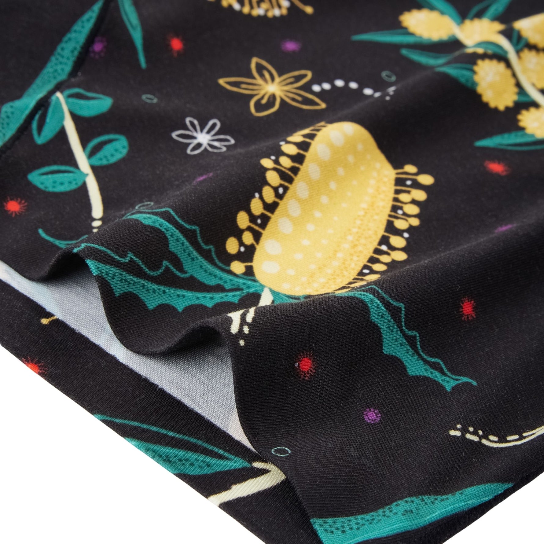 Detailed view of Golden Snug fabric hem featuring bold floral prints on black, with rich tones