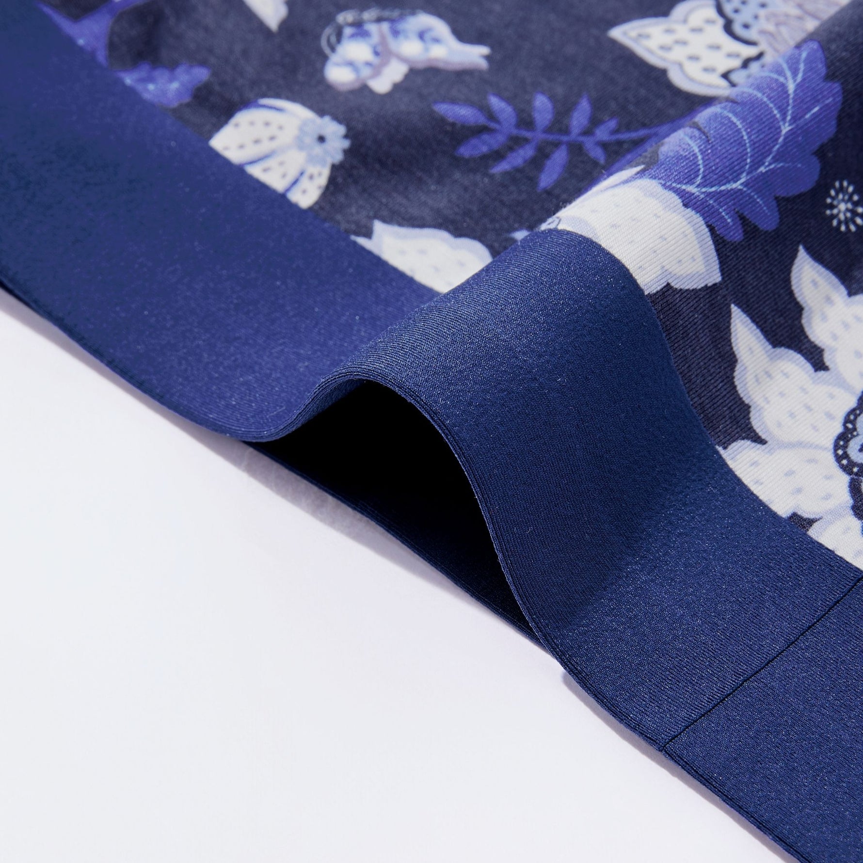 Close-up of navy blue waistband fabric with white floral patterns on a white background