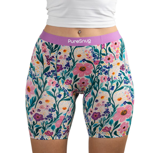 Model wearing Meadow muse floral-patterned PureSnug boxer brief with vibrant pink, yellow, and purple flowers and a lavender waistband.