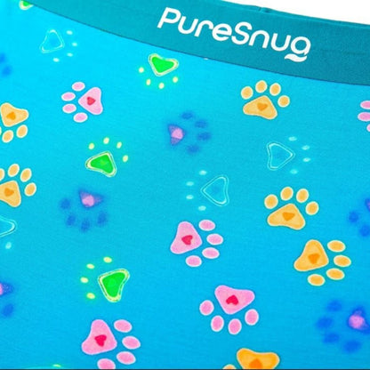 Close-up of bright blue fabric featuring colorful paw prints and geometric shapes with the "PureSnug" logo at the top.