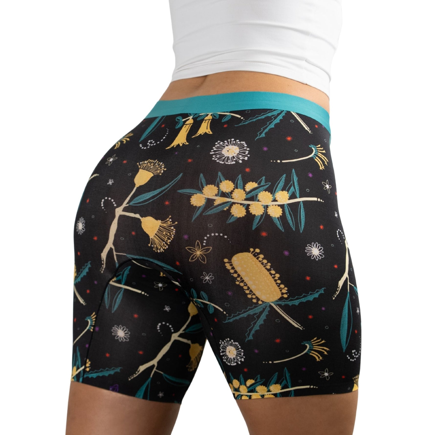 Person wearing black PureSnug boxer briefs with colorful floral pattern featuring yellow and turquoise accents,