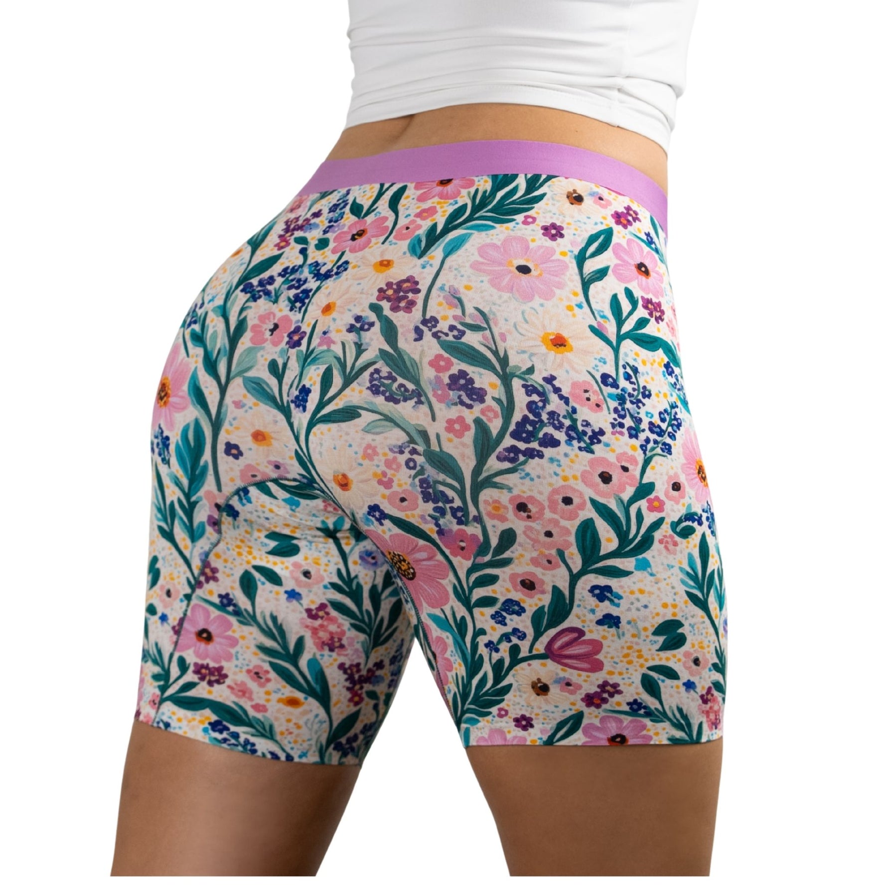 Woman wearing floral-patterned PureSnug boxer briefs with vibrant pink, purple, and green design