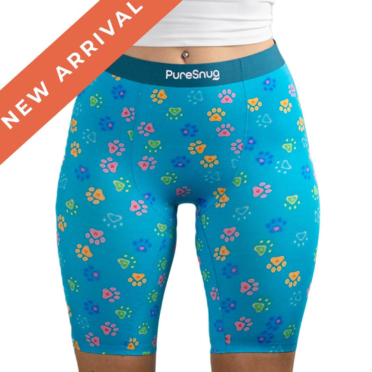 New high-waisted Pawfect Biker short in paw and heart prints, labeled "PureSnug." A red "New Arrival" banner overlays the image, conveying a playful and trendy tone.