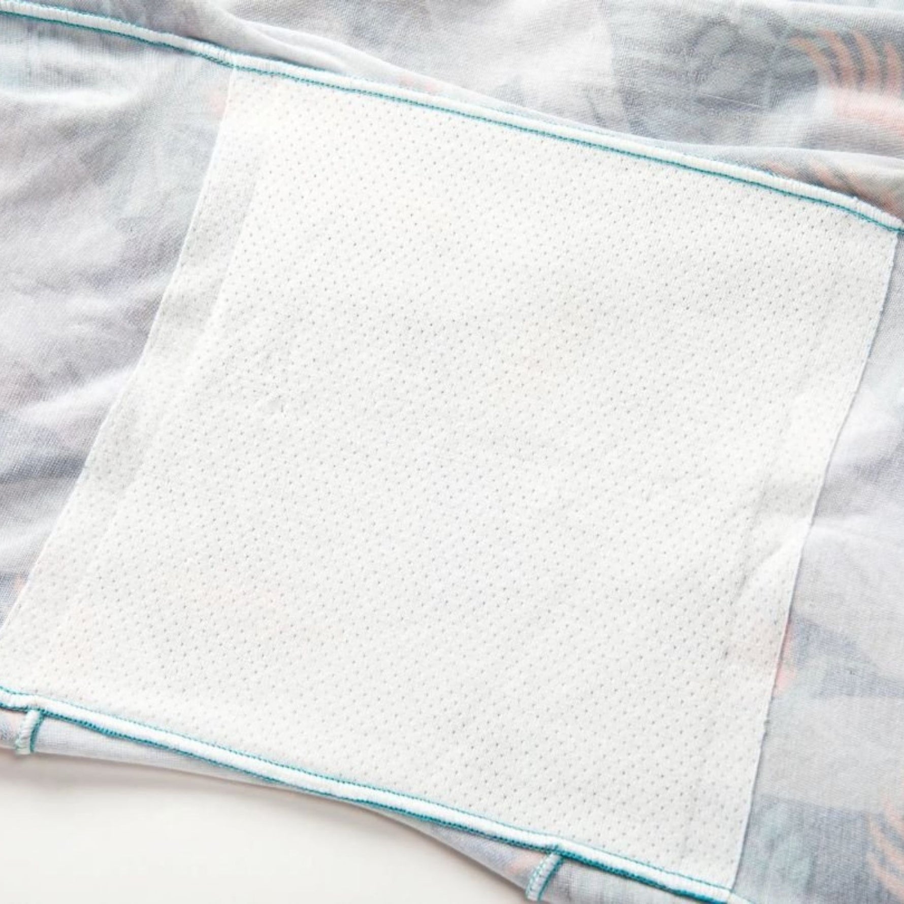 Soft light fabric with pastel blue trim and a textured white patch, simple and clean.