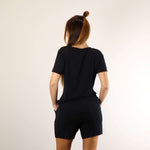 Woman wearing a very soft black PureSnug lounge V-neck lounge tee and black lounge shorts, back view.