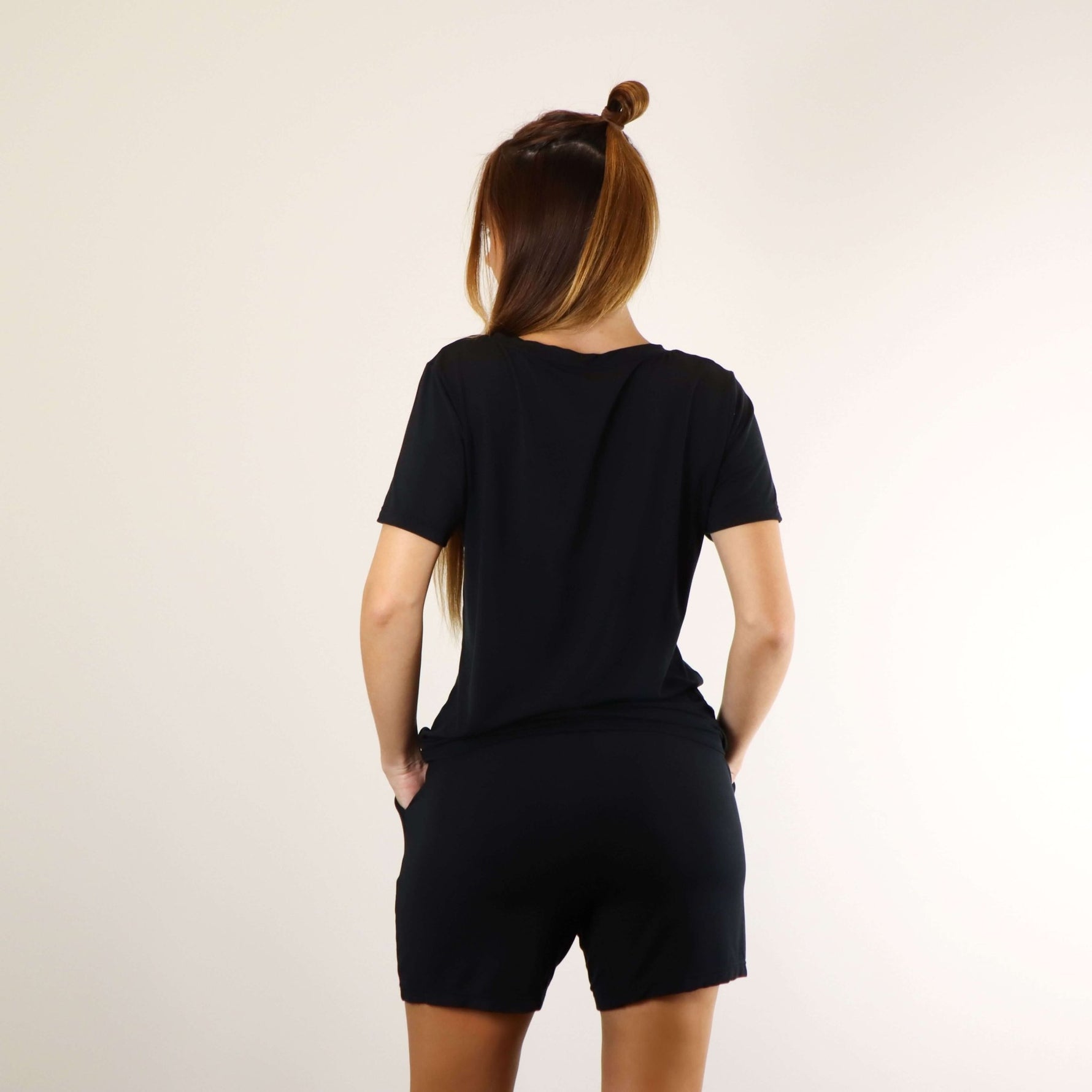 Woman wearing a very soft black PureSnug lounge V-neck lounge tee and black lounge shorts, back view.