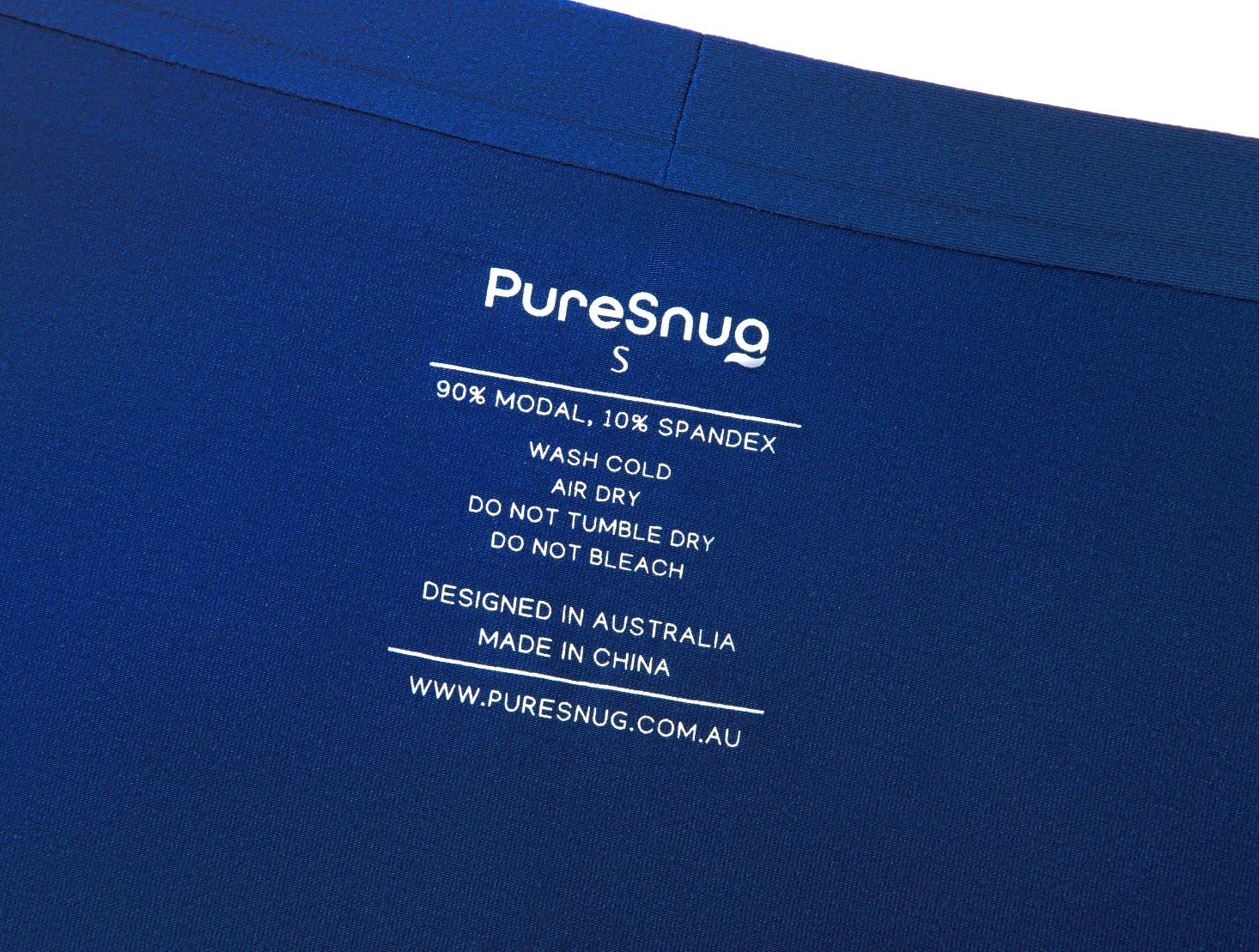 Close-up of a garment care label on blue fabric. It reads "PureSnug S, 90% Modal, 10% Spandex," with washing instructions.