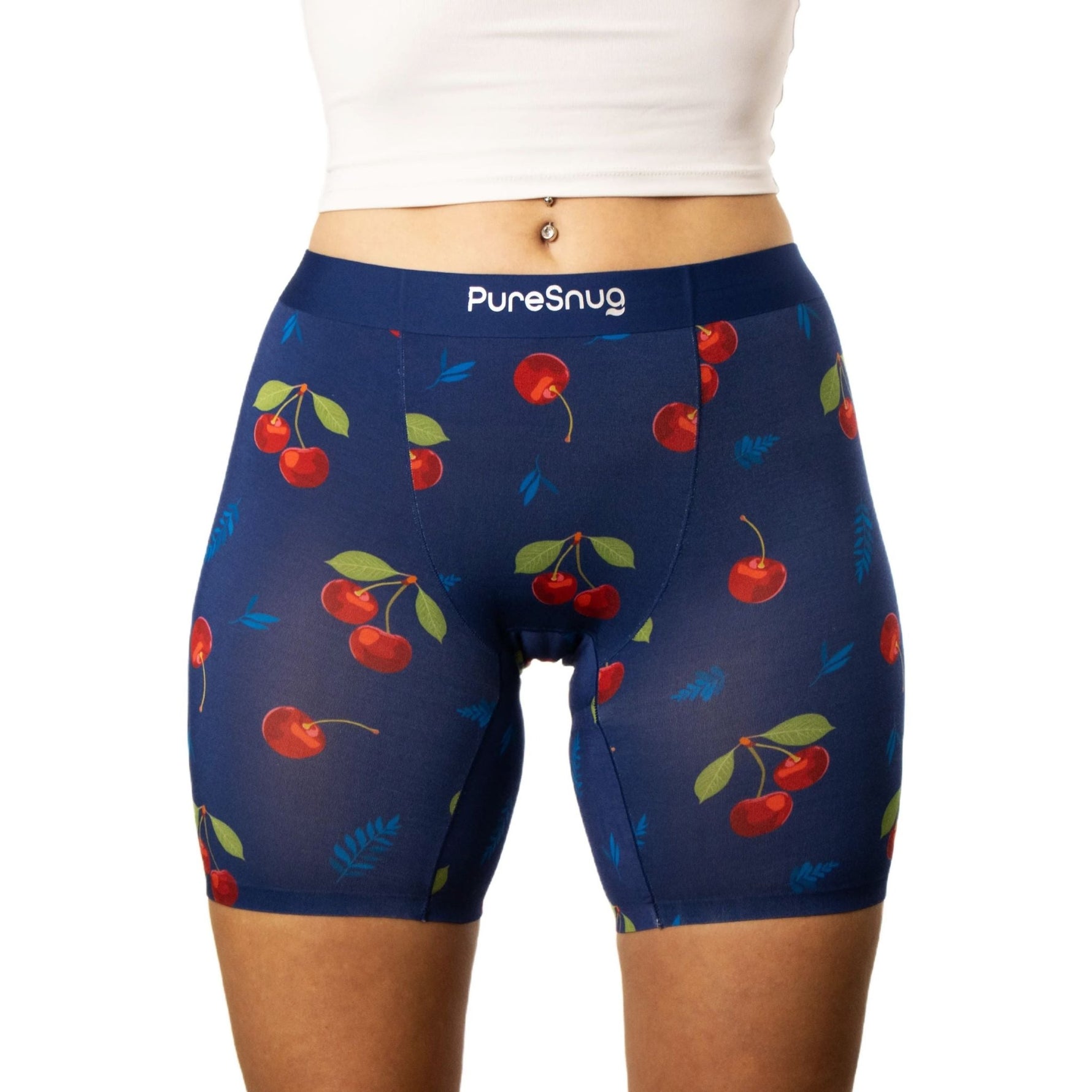 A person wearing navy blue shorts with red cherries and green leaves pattern. The waistband reads “PureSnug.”