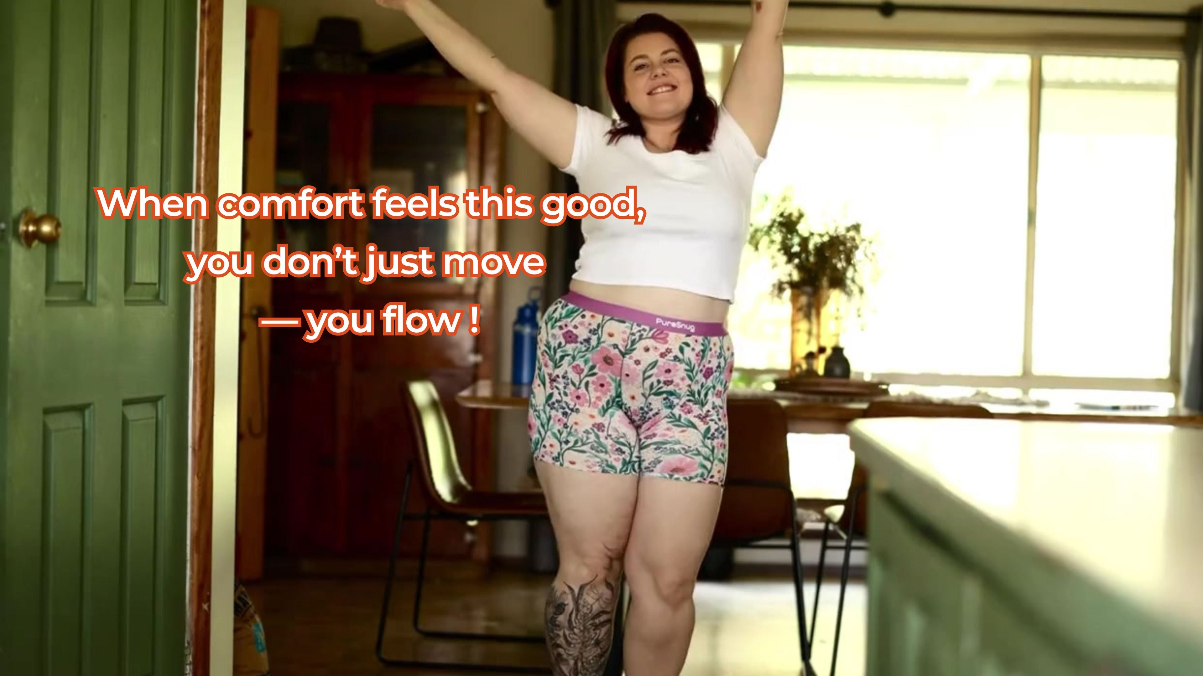 Load video: A confident woman dancing in a  living room, wearing a white crop top and floral PureSnug boxer briefs — showcasing size-inclusive, no-ride-up underwear designed for comfort and joyful movement.